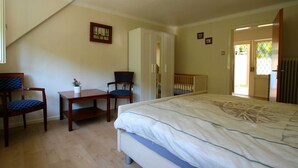 Une chambre à coucher comprenant un lit, deux chaises, une petite table et une armoire.