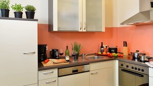 A kitchen with white cabinets, a stainless steel oven, and a countertop with various items including a coffee maker, wine bottle, and potted plants. - Modern Apartment in Morz in the Hunsruck (Buch)