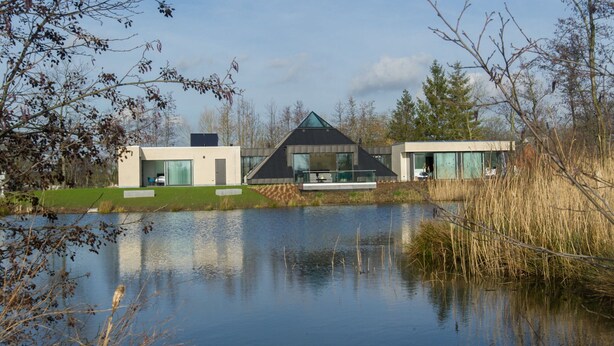 A modern house with a glass facade, a pond in the foreground, and a grassy area. - Lovely Holiday Home 'walleken' With a Pond (Aalst)
