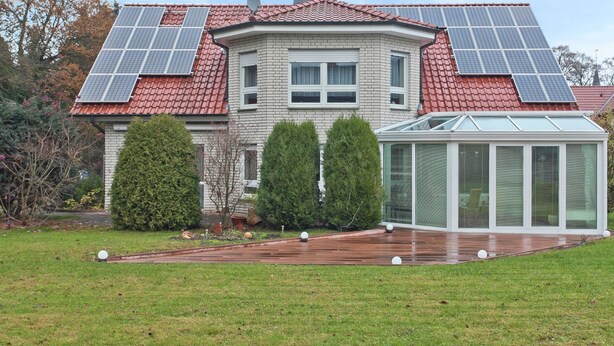 A house with a red-tiled roof, solar panels, a conservatory, and a well-maintained lawn. - Furnished Apartment in Nieheim Germany near Forest (Nieheim)