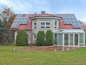A house with a red-tiled roof, solar panels, a conservatory, and a well-maintained lawn. - Furnished Apartment in Nieheim Germany near Forest (Nieheim)