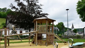Un'area giochi con una struttura in legno per arrampicarsi, scivoli e altalene.