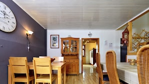 Zona pranzo con mobili in legno, una sveglia a parete e un armadietto.