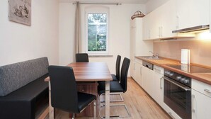 A modern kitchen with a dining area, featuring a wooden table, black chairs, and a built-in oven. - Ferienhaus in Rechenberg-bienemuehle (Rechenberg-Bienenmuehle)