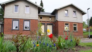 A two-story house with a brick facade and a small garden with tulips and other flowers. - Ferienhaus in Rechenberg-bienemuehle (Rechenberg-Bienenmuehle)