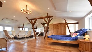 A spacious room with a wooden floor, a bed with blue bedding, and a chandelier. - Exquisite Mansion in Pugholz near Sea (Hasselberg)