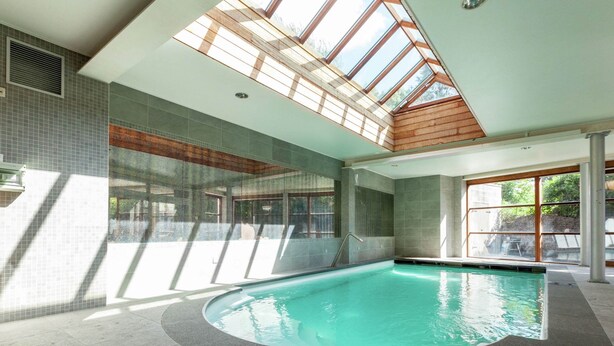 Una piscina interior con tragaluces, paredes de azulejos y vistas al exterior.