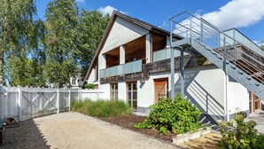 Una casa moderna de dos pisos con una terraza de madera y una escalera de metal.