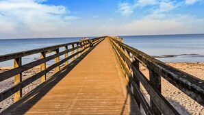 A wooden pier extending into calm waters with a clear sky above. - Ferienhaus in Thorstorf mit Garten (Warnow)