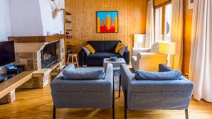Un salon confortable avec une cheminée, un ensemble de canapés, une table basse et un téléviseur.