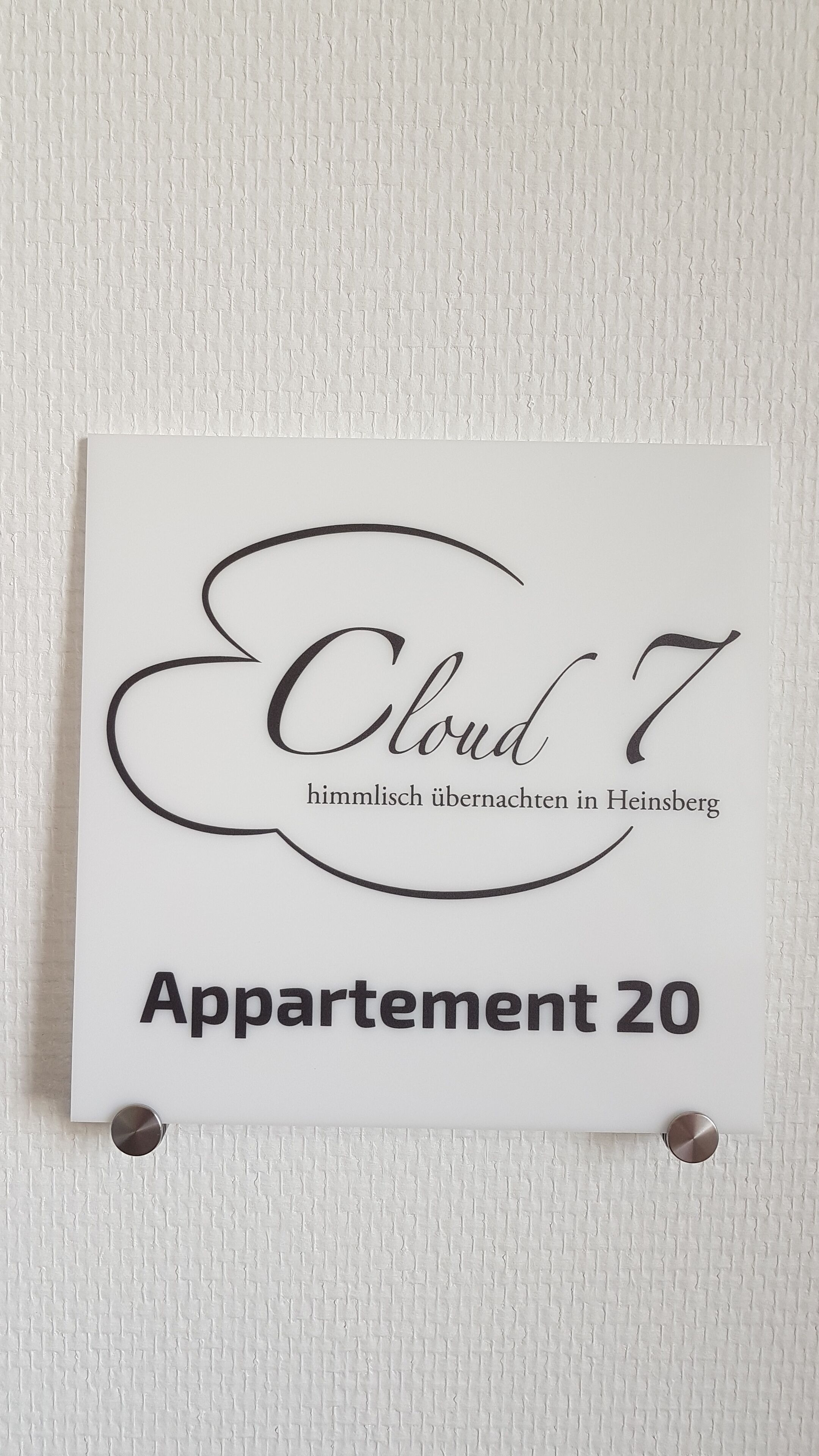 A sign for 'Cloud 7' with the text 'himmlich übernachtet in Heinsberg' and 'Appartement 20' indicating a room in Heinsberg.