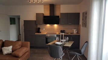Una cocina moderna con comedor, un sofá y una cafetera.
