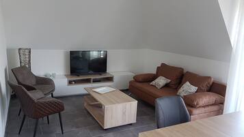 Una sala de estar moderna con sofá, mesa de centro, televisor y una silla.