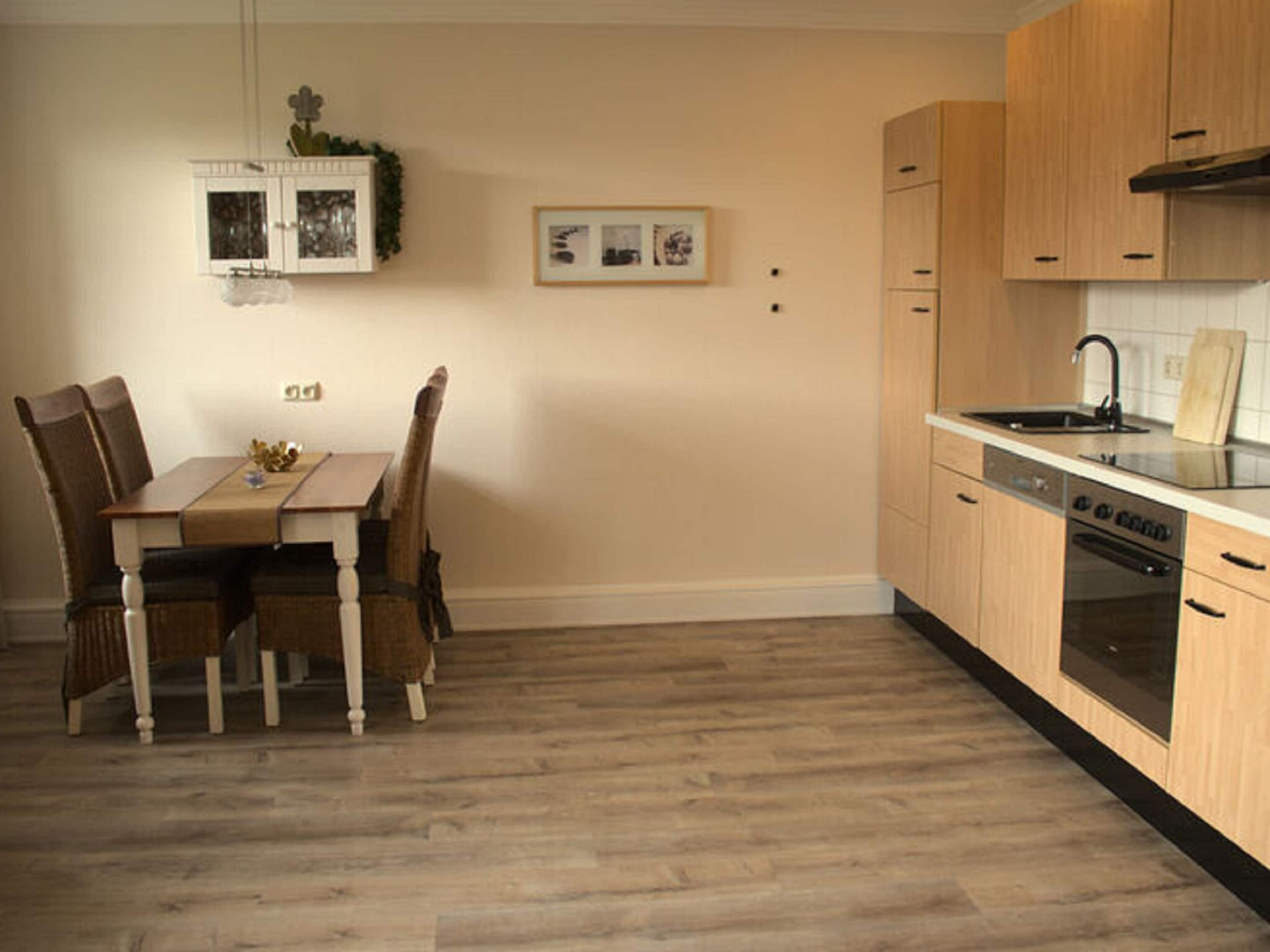 Una cocina con armarios de madera, lavavajillas y una mesa de comedor con sillas.