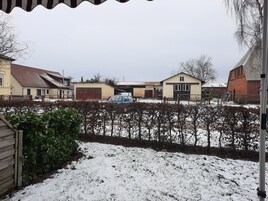 A residential area with houses, a blue car, and a snow-covered ground.