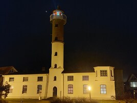 A lighthouse with a tall tower and a shorter building attached to it.