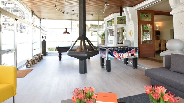 A modern indoor space with a fireplace, a pool table, and a cozy seating area. - Former Hotel in the Centre and Near the Beach in Panne (De Panne)