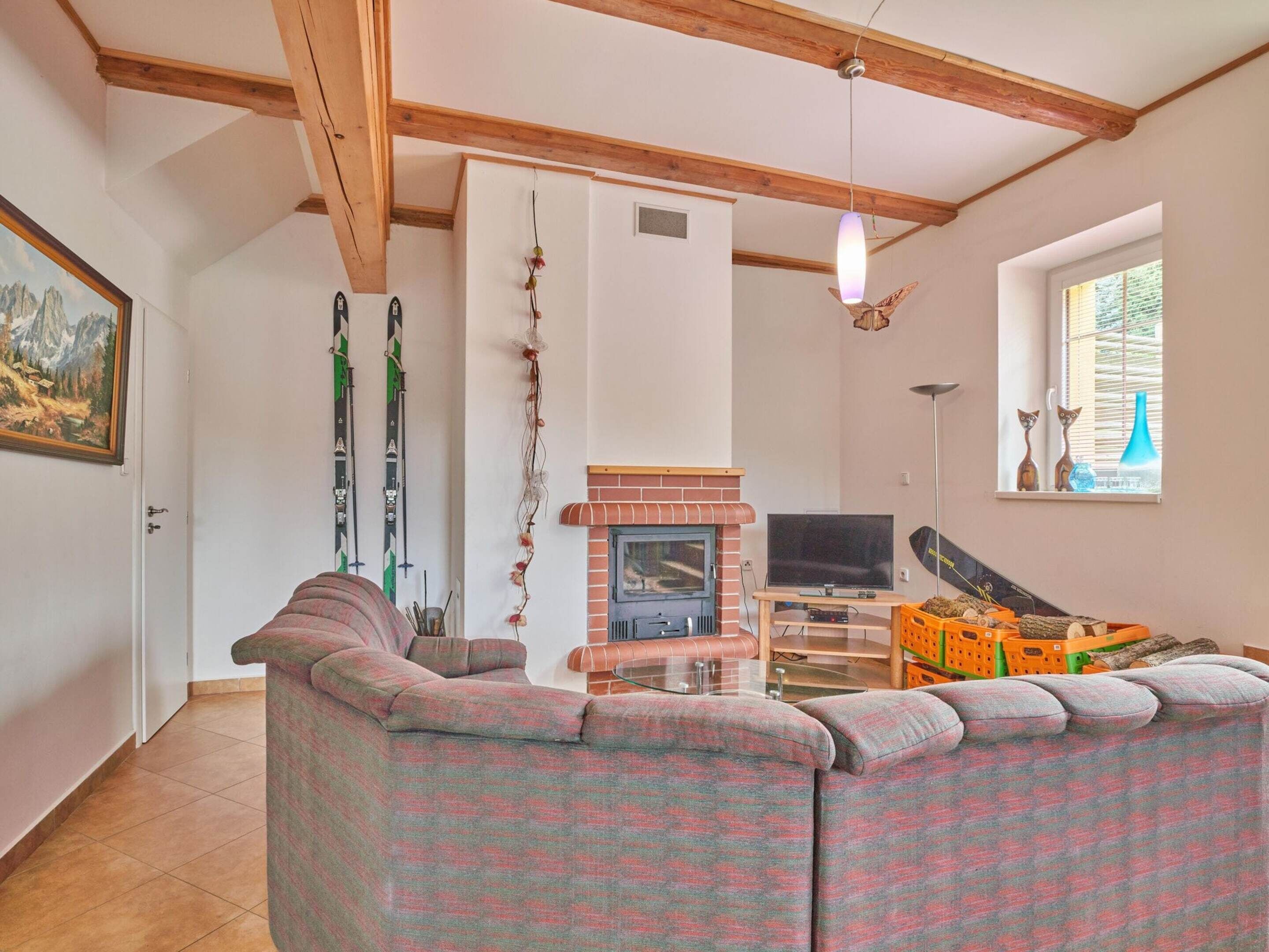 A living room with a fireplace, a sofa, skis, and a TV.