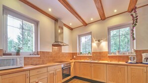 Una cocina con armarios de madera, horno empotrado, microondas y pileta.