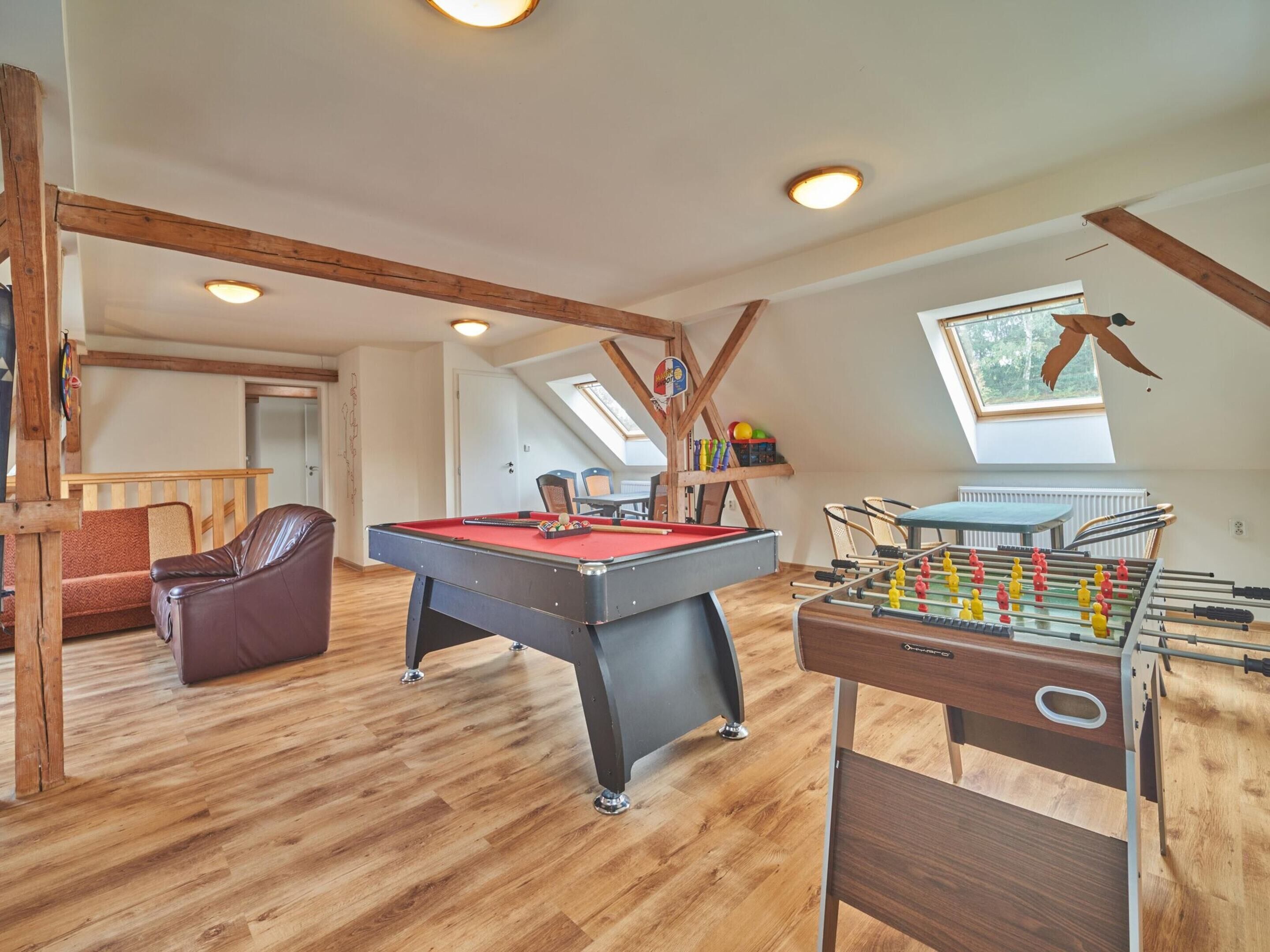 A spacious room with a pool table, foosball table, and a cozy seating area.