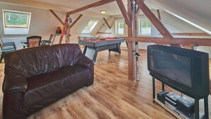 Un loft acogedor con mesa de billar, sofá de cuero y televisor.