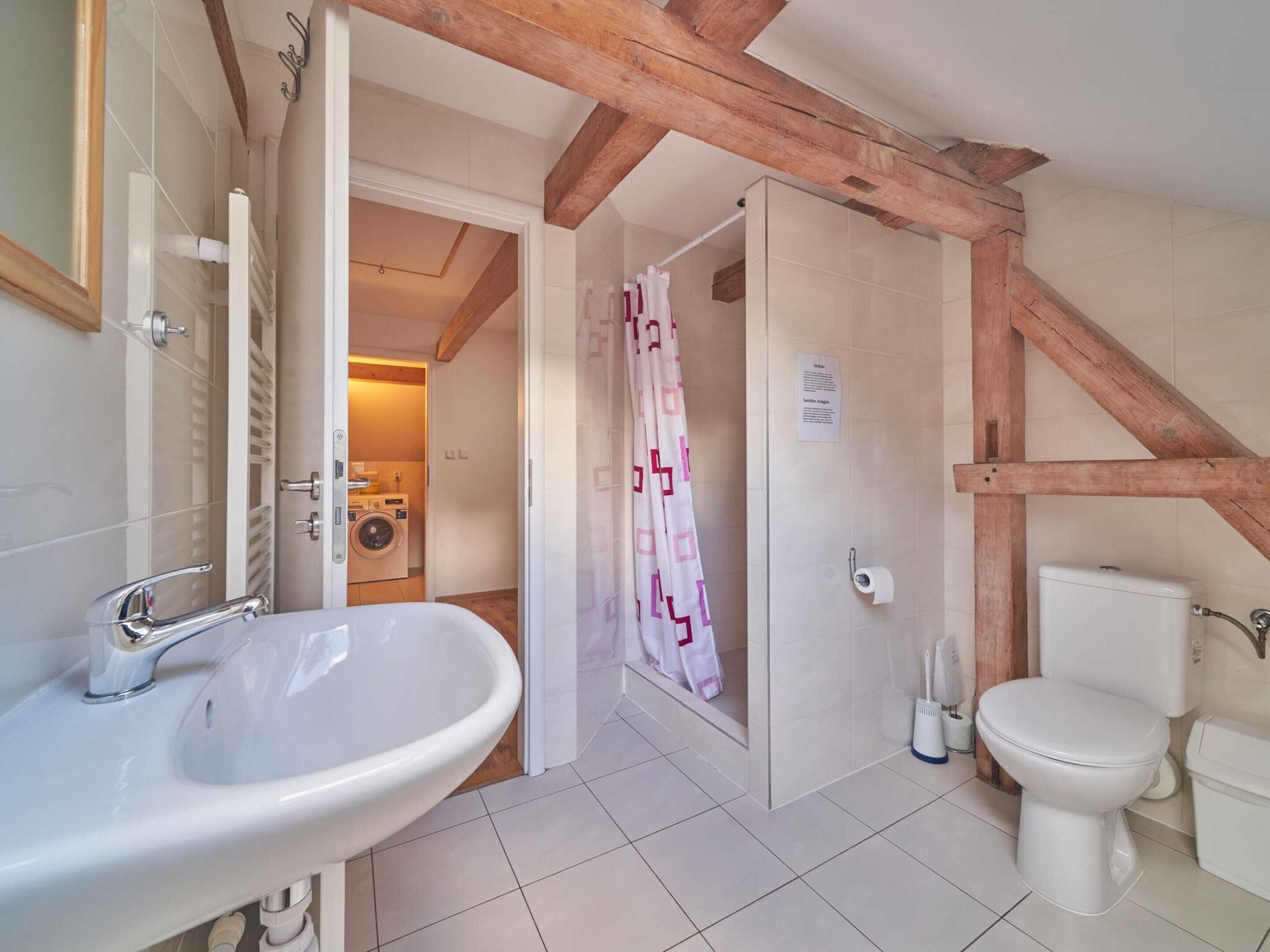 A bathroom with a sink, toilet, and shower area.