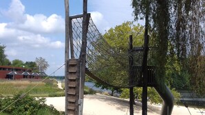 A playground with a climbing structure, a rope bridge, and a sandy area.
