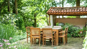 A wooden table and chairs set outdoors with a tiled roof structure in the background. - Cosy and Snug Holiday Home With Joint Swimming Pool (Tessenderlo)