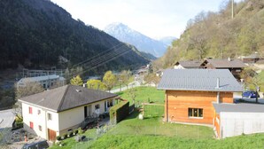 Un village rural avec des maisons, une petite route et des montagnes en arrière-plan.
