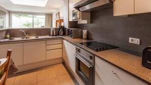 A modern kitchen with a built-in oven, microwave, and stovetop. There is a window providing natural light and a view of the outdoors. - Holiday Home in Kortrijk for 8 Person (Kortrijk)