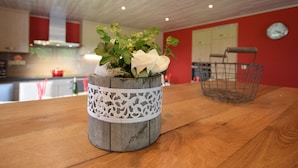 Una mesa de madera rústica con una maceta decorativa que contiene flores blancas y follaje verde.
