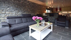 Una sala de estar moderna con pared de piedra, sofá de cuero y una mesa de centro con flores.
