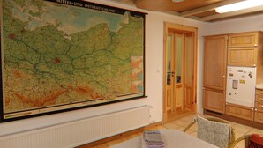 A room with a large map on the wall, a table with a book, and wooden cabinets. - Alt Krassow Lakeside Retreat (Lalendorf)