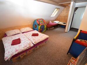 A bedroom with two beds, a play area, and a door leading to another room. - House in Bohemian Near Ski Slope (Blatno)