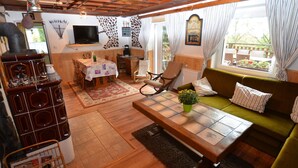 A cozy living room with a wooden ceiling, a green sofa, a wooden coffee table, and a television. - House in Bohemian Near Ski Slope (Blatno)