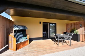 An outdoor patio with a wooden deck, a covered seating area, and a dining table with chairs. - Wohnung in Barnekow mit Eigener Terrasse (Barnekow)