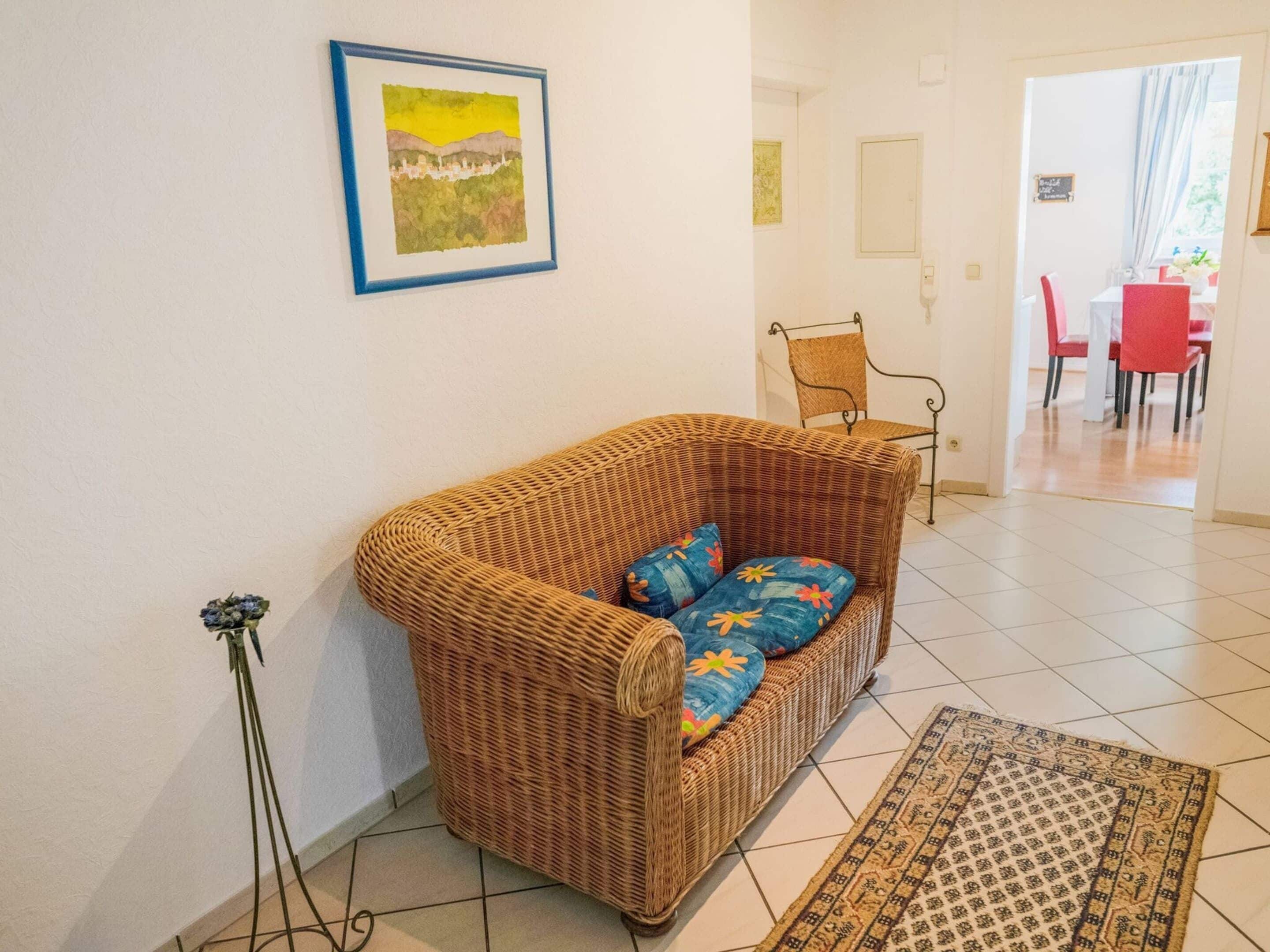 A living room with a wicker sofa, a patterned rug, and a framed picture on the wall.