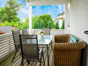 A covered outdoor patio with a table and chairs, surrounded by greenery and buildings in the background. - Apartment in Medebach Near Orketal Reserve (Medebach)