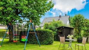 A backyard with a swing set, a small shed, and a dining table with chairs. - Apartment in Medebach Near Orketal Reserve (Medebach)