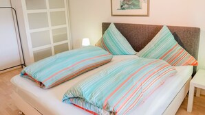A bed with striped bedding, a bedside table, a lamp, and a framed artwork on the wall. - Apartment in Medebach Near Orketal Reserve (Medebach)