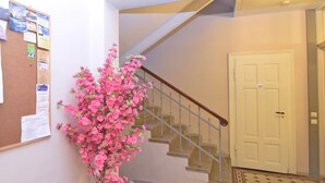 A staircase with a handrail, a door, and a bulletin board with various notices. - Gruppenhaus mit German Heimkino, 18 Personen (Treuen)