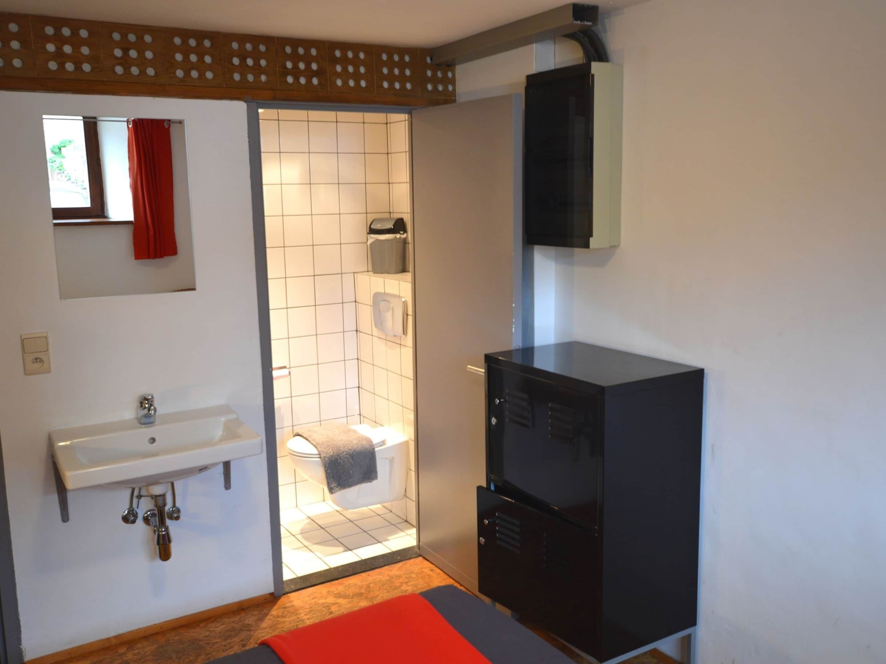 Un bany petit amb un lavabo blanc, vàter i zona de dutxa.