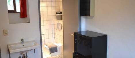 Een kleine badkamer met een witte wastafel, toilet en douche.