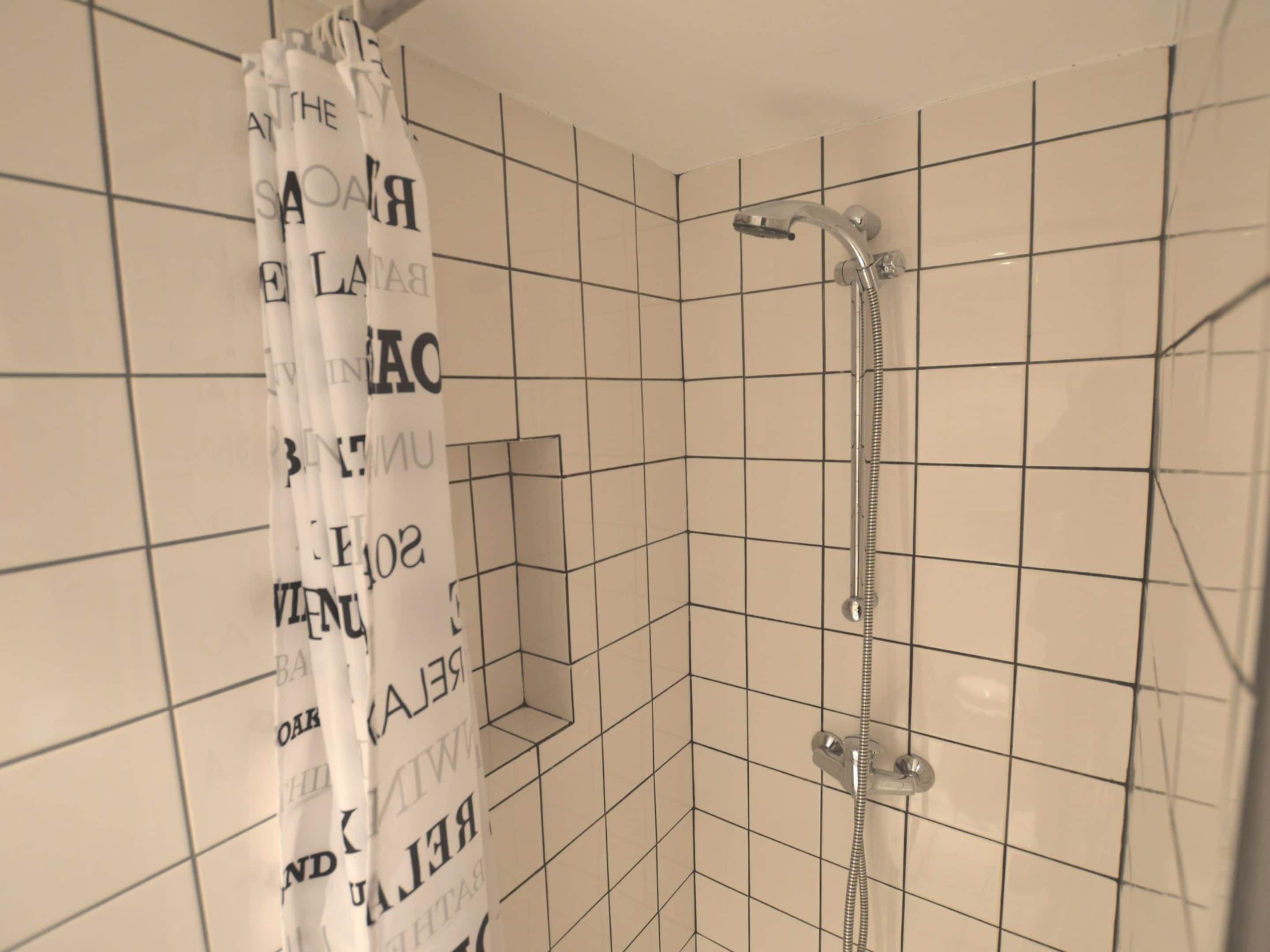 A shower area with a tiled wall and a showerhead.