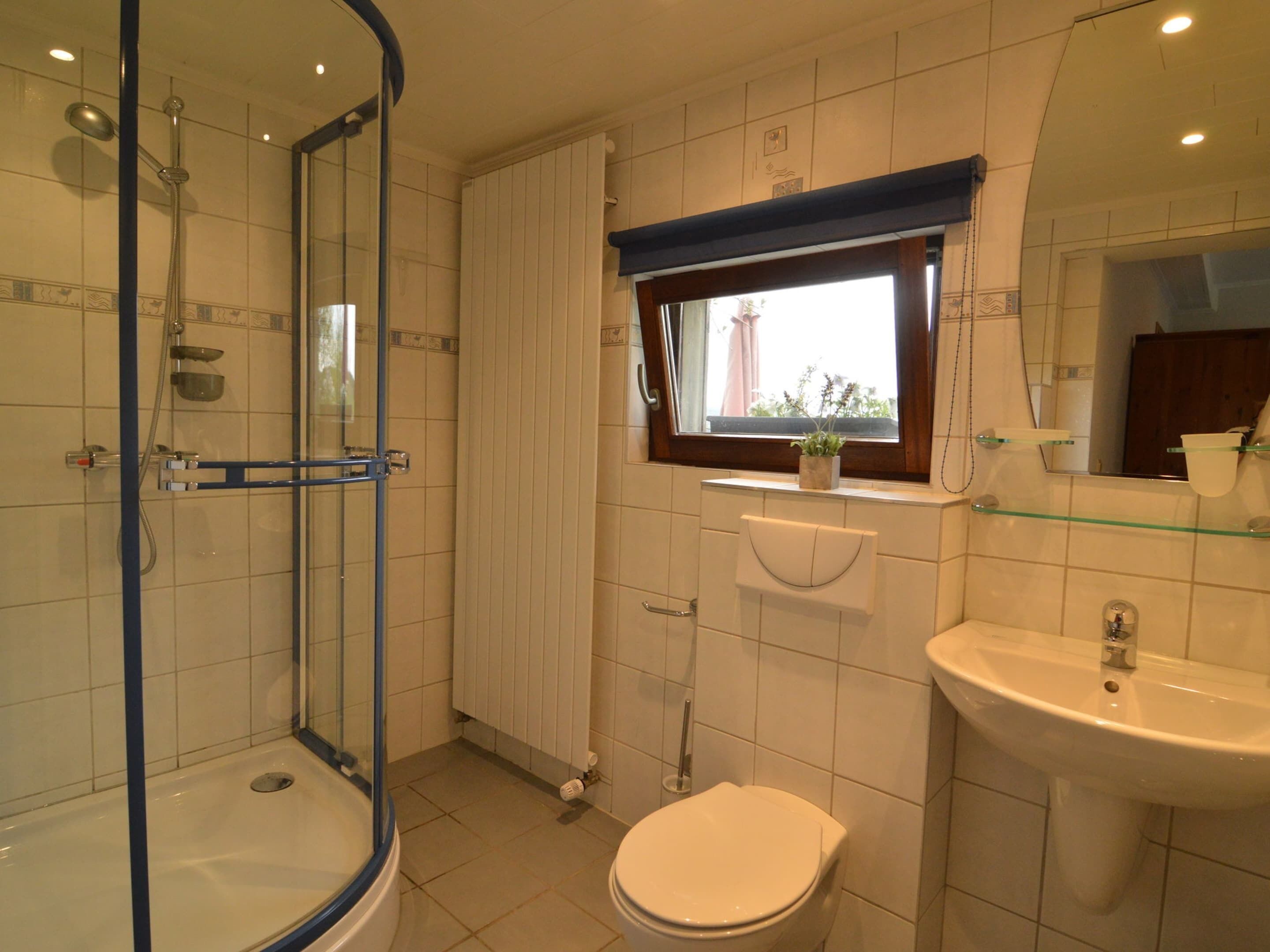 Une salle de bain avec une douche à parois de verre, des toilettes et un lavabo.