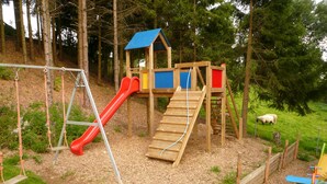 Une aire de jeux avec un toboggan, des balançoires et une structure d’escalade.