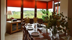 Un coin repas avec une table dressée pour quatre personnes, un buffet et une vue sur la verdure à l’extérieur.