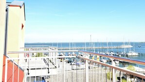 Ein Yachthafen mit vertäuten Booten, ein klarer Himmel und ein Gebäude mit einem Balkon mit Blick auf das Wasser.