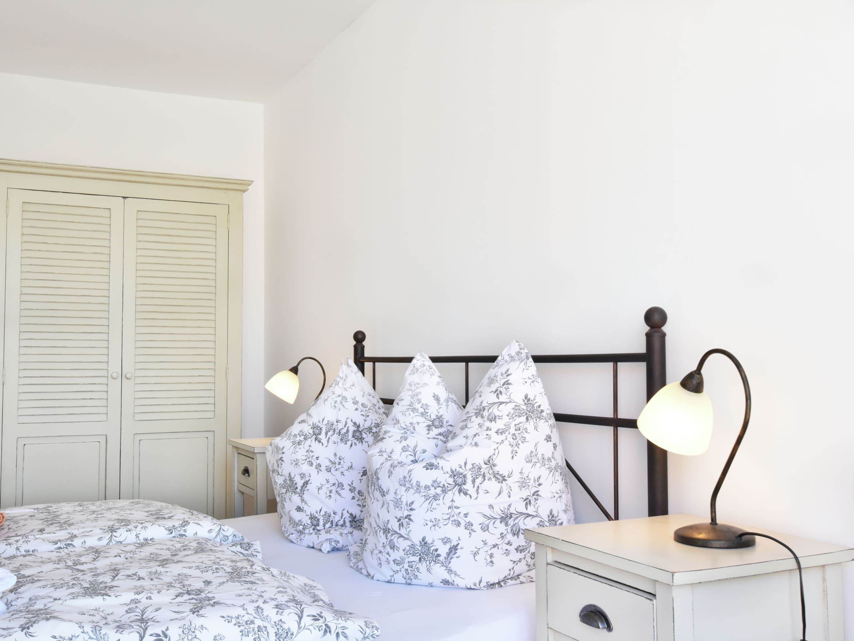 Un dormitorio con una cama, dos mesitas de noche, un aparador y un armario.