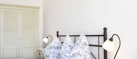 A bedroom with a bed, two nightstands, a dresser, and a wardrobe.